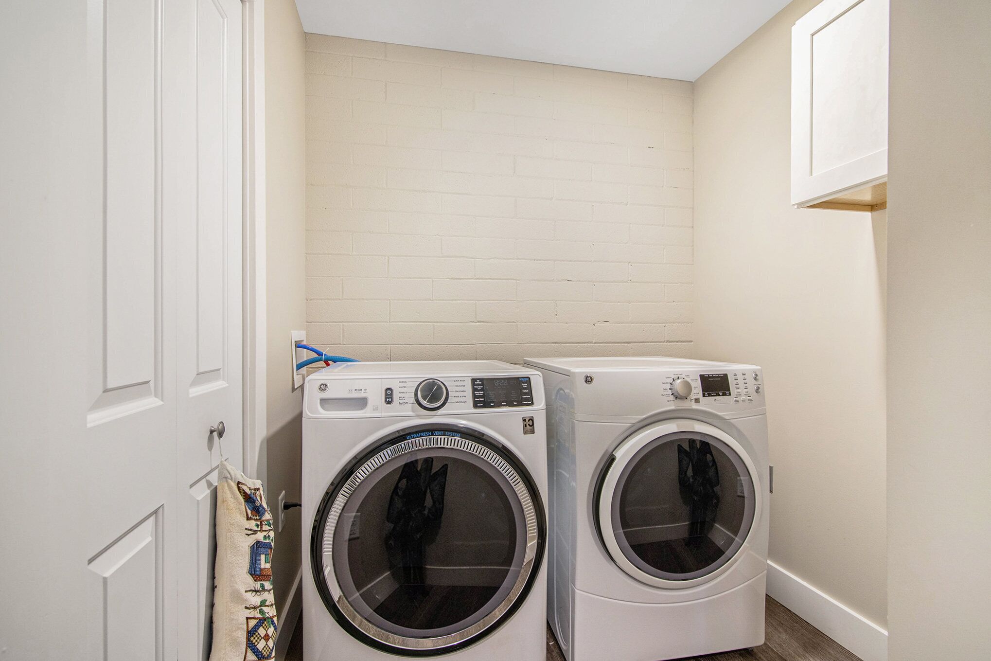 A laundry room with two front-loading washing machines and a white door.