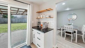 Une cuisine compacte comprenant un plan de travail, des placards et un petit coin repas avec une table et des chaises.