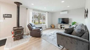 Un salon moderne avec une cheminée, un canapé, un fauteuil inclinable et un meuble pour la télévision.