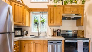 Een moderne keuken met houten kastjes, roestvrijstalen apparatuur en hangplanten.