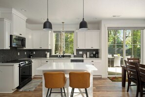 A modern kitchen with white cabinetry, black and white backsplash, and two pendant lights.