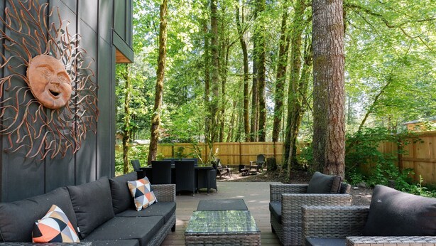 An outdoor patio with wicker furniture, a sun-shaped wall decoration, and a wooden deck.