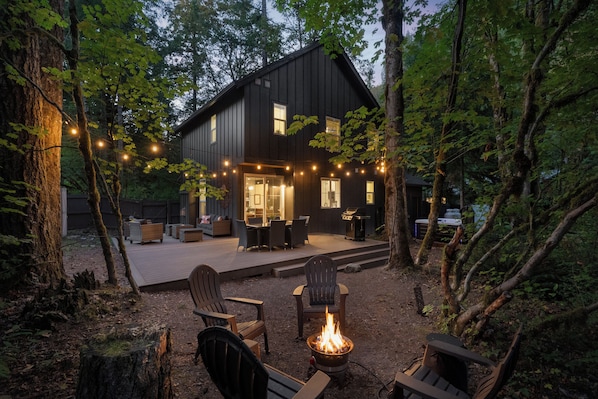 A modern house with a deck, outdoor furniture, and a fire pit.
