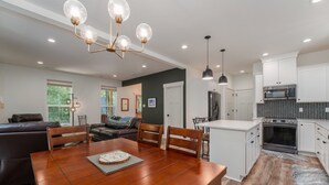 A modern kitchen with white cabinets, a black microwave, and a stainless steel oven.