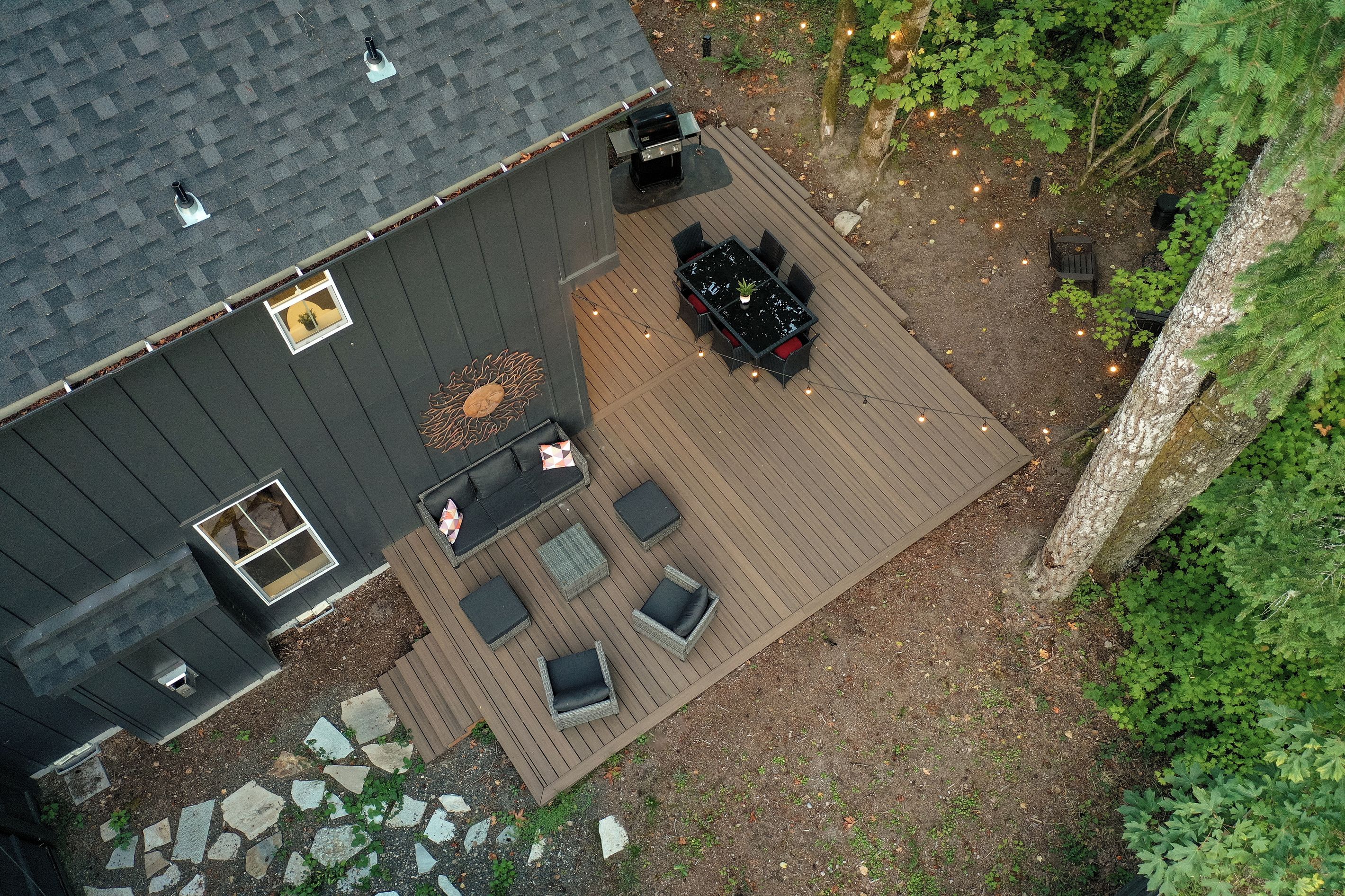 An aerial view of a house with a patio area, a barbecue grill, and a small garden.