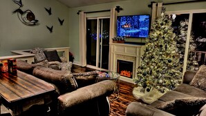 Uma sala de estar acolhedora com lareira, televisão e uma árvore de Natal decorada.