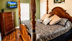 Um quarto com uma cama de dossel, cômoda, televisão e um quadro na parede.