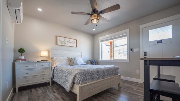 A bedroom with a bed, bedside table, lamp, ceiling fan, and a window. - Charming Kanab suite #3, Basecamp to Zion, Bryce (Kanab)