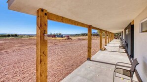 A covered outdoor area with wooden beams and concrete flooring, leading to a building with a dark exterior wall and a window. - Charming Kanab suite #3, Basecamp to Zion, Bryce (Kanab)