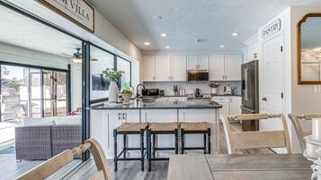 A modern kitchen with white cabinets, a central island, and a dining area with a table and chairs.