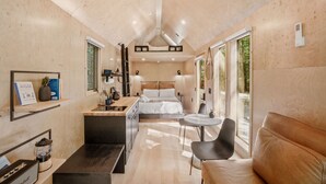 Una habitación compacta y moderna con cama, mesita de noche y una pequeña zona de estar.