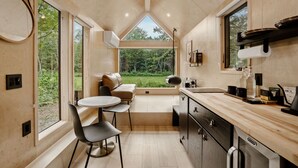 A modern kitchen with a dining area, large windows, and a view of the outdoors.