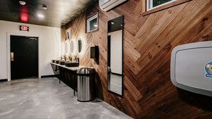 A restroom with wooden paneling, a sink with mirrors, and an exit sign.
