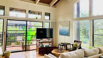 Un salón amplio con una televisión grande, asientos cómodos y vistas amplias a través de grandes ventanales.