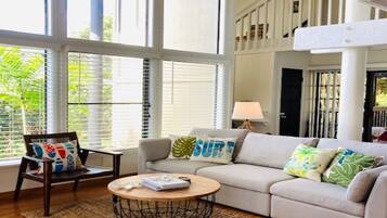 A spacious living room with a large window, a sofa, a coffee table, and a chair.