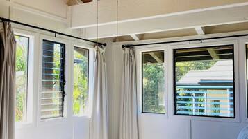 A bedroom with a bed, a ceiling fan, and windows with curtains.