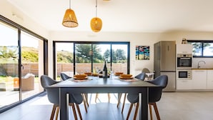 Une cuisine moderne avec un coin repas, de grandes fenêtres et une vue sur l’extérieur.