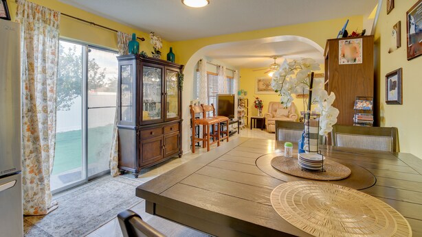 Un coin repas comprenant une table en bois, des chaises, un buffet et une vue à travers une porte vitrée.