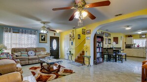 Un salon avec un canapé, une table basse et un ventilateur de plafond. Un escalier mène à un autre niveau.