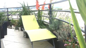 Una silla amarilla de descanso en un balcón con plantas y flores en macetas.