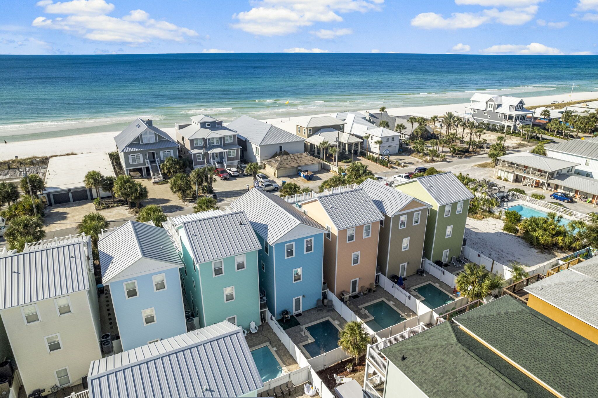 A coastal residential area with multiple houses, a beach, and a swimming pool.
