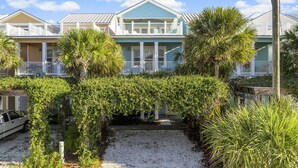 A row of coastal-style houses with balconies, surrounded by lush greenery and a gravel driveway. - Spectacular Gulf Views w/ Private Pool! Remarkable 3BR 3.5ba Bedding for 12! (Panama City Beach)