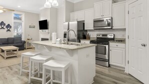 A modern kitchen with white cabinetry, stainless steel appliances, and a central island with bar stools. - Spectacular Gulf Views w/ Private Pool! Remarkable 3BR 3.5ba Bedding for 12! (Panama City Beach)