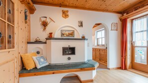 A cozy room with a built-in bench, wooden ceiling, and a fireplace. - Ferienhaus Taubenstein by Interhome (Neukirchen am Großvenediger)