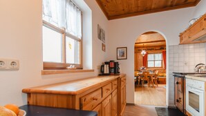 A kitchen with wooden cabinets, a black countertop, and a window with a view. - Ferienhaus Taubenstein by Interhome (Neukirchen am Großvenediger)