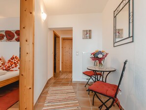 A hallway with a bed, a dining table with chairs, and a mirror on the wall. - Ferienhaus Taubenstein by Interhome (Neukirchen am Großvenediger)