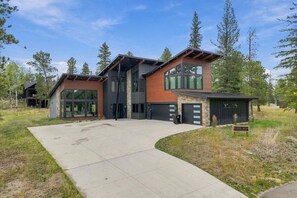 A modern two-story house with a garage, large windows, and a driveway.