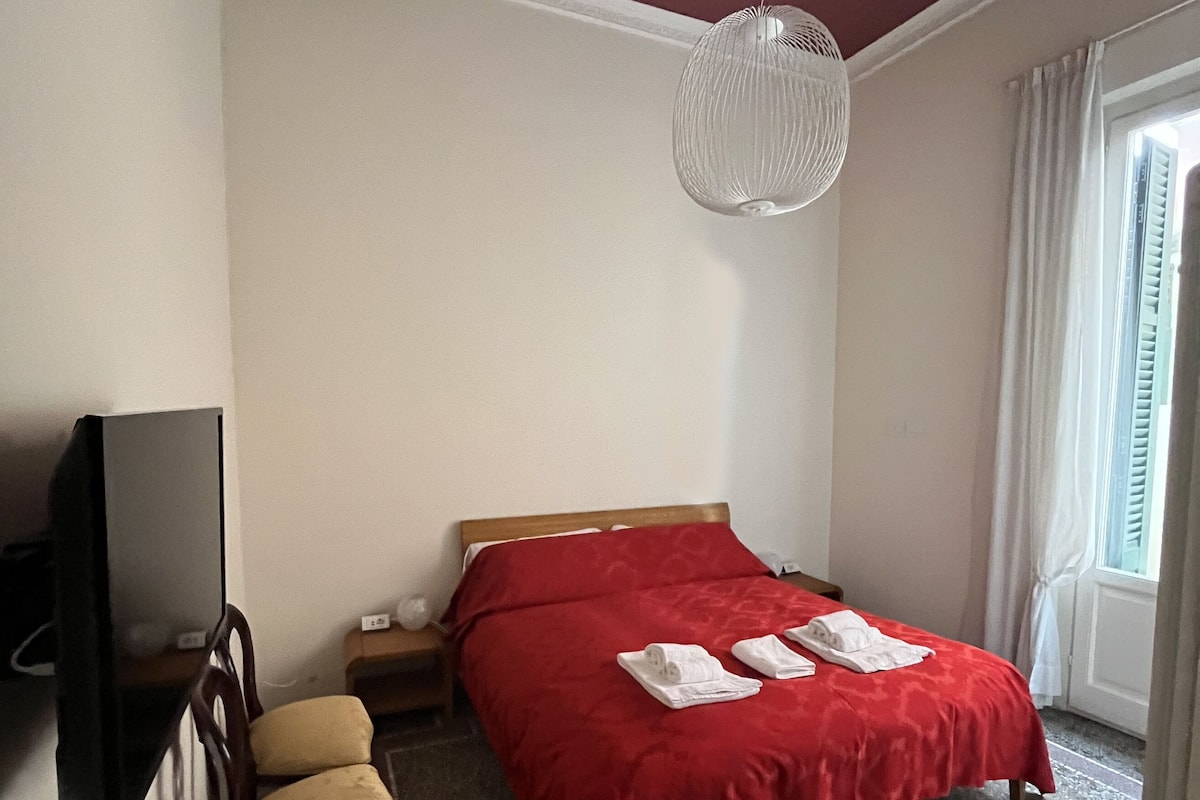 Une chambre d’hôtel avec un lit, une télévision, un bureau et une fenêtre avec des rideaux.