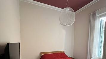 Hotellihuone, jossa on sänky, televisio, työpöytä ja ikkuna, jossa on verhot.