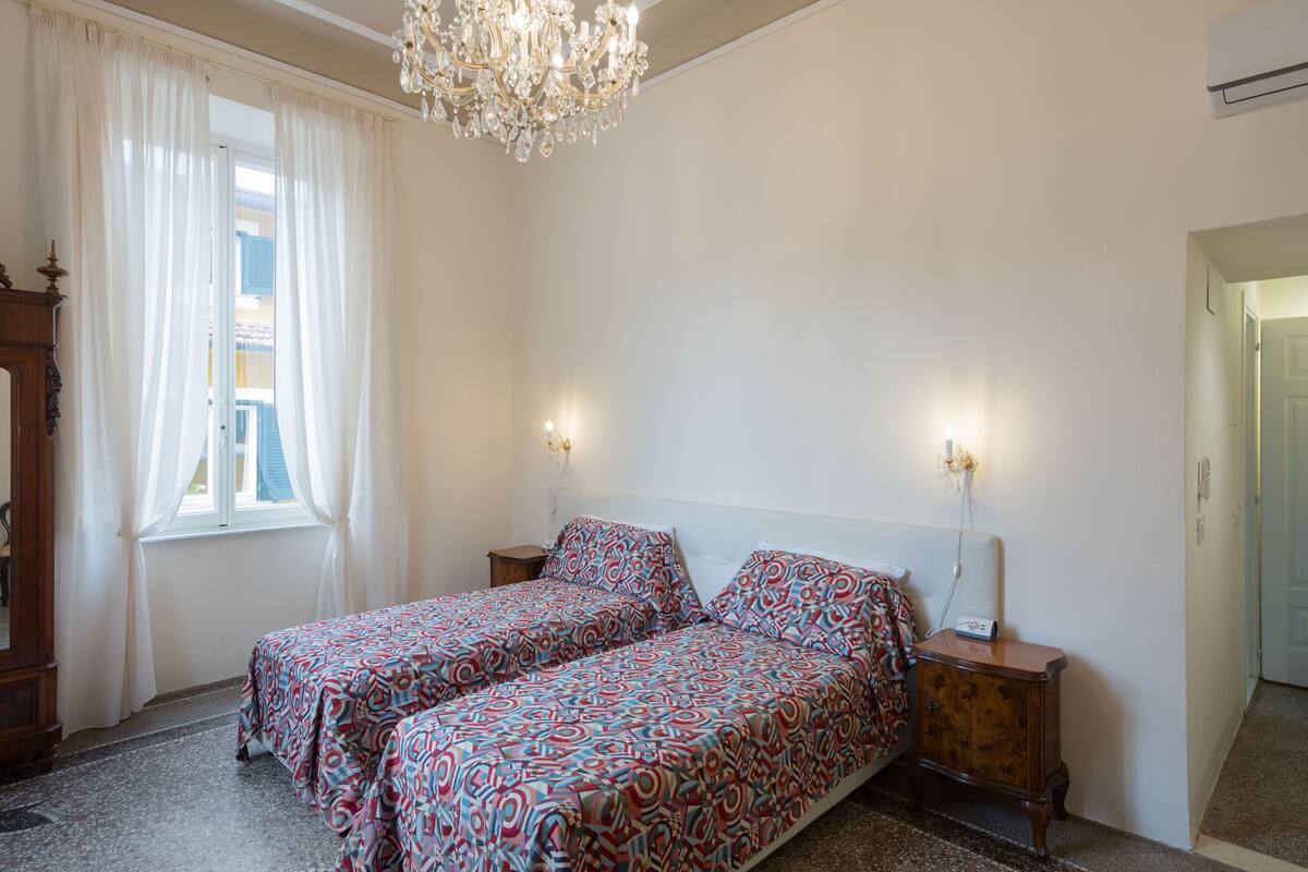 Une chambre avec deux lits, un lustre et une vue sur l’extérieur.
