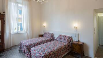 Une chambre avec deux lits, un lustre et une vue sur l’extérieur.