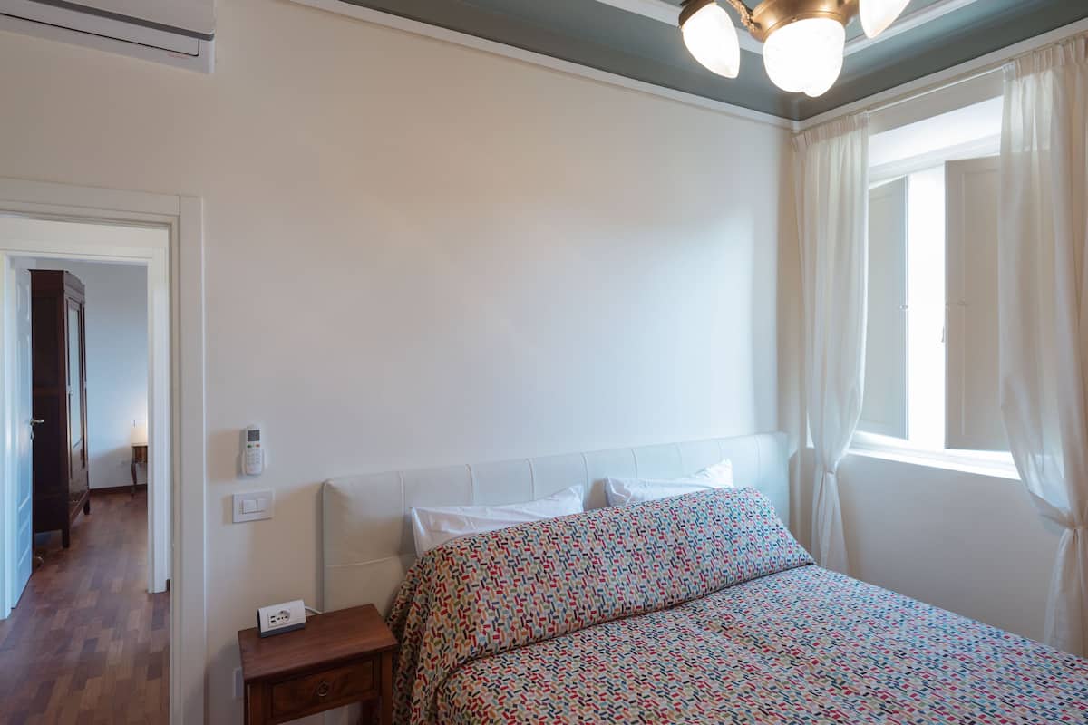 Une chambre à coucher avec un lit, une table de chevet et une fenêtre avec des rideaux.