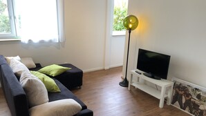 A modern living room with a black sofa, a white TV stand, and a floor lamp.