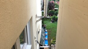A narrow stairway leading to a garden area with a blue water feature and a wooden fence.