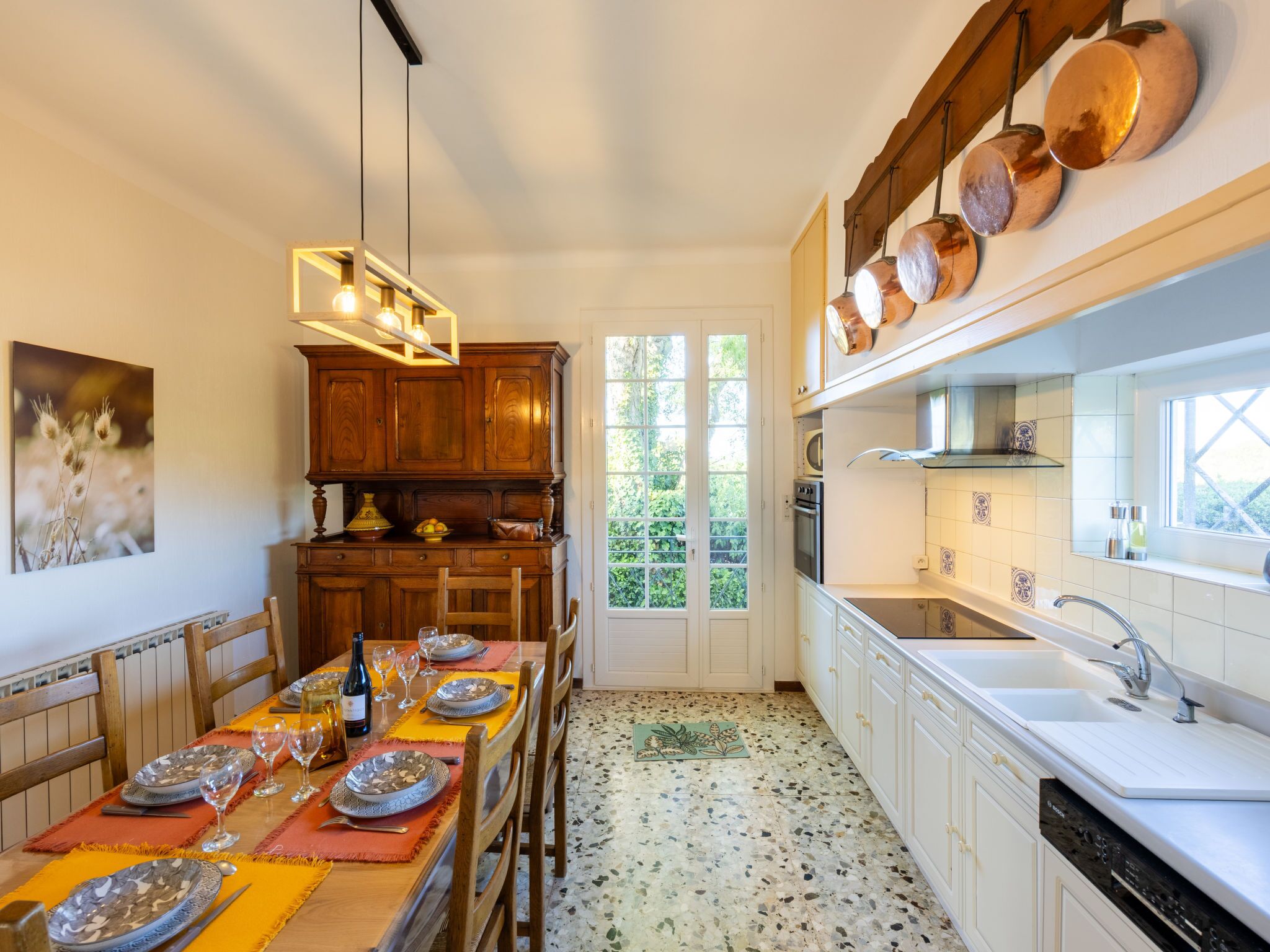 A modern kitchen with wooden cabinets, a dining table set for six, and a large window.
