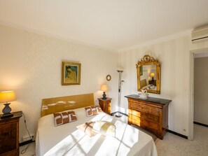 A hotel room with a bed, bedside lamps, a dresser, a mirror, and a painting on the wall. - Le Clos Saint Emilie (Tennis & piscine) by Interhome (Béziers)