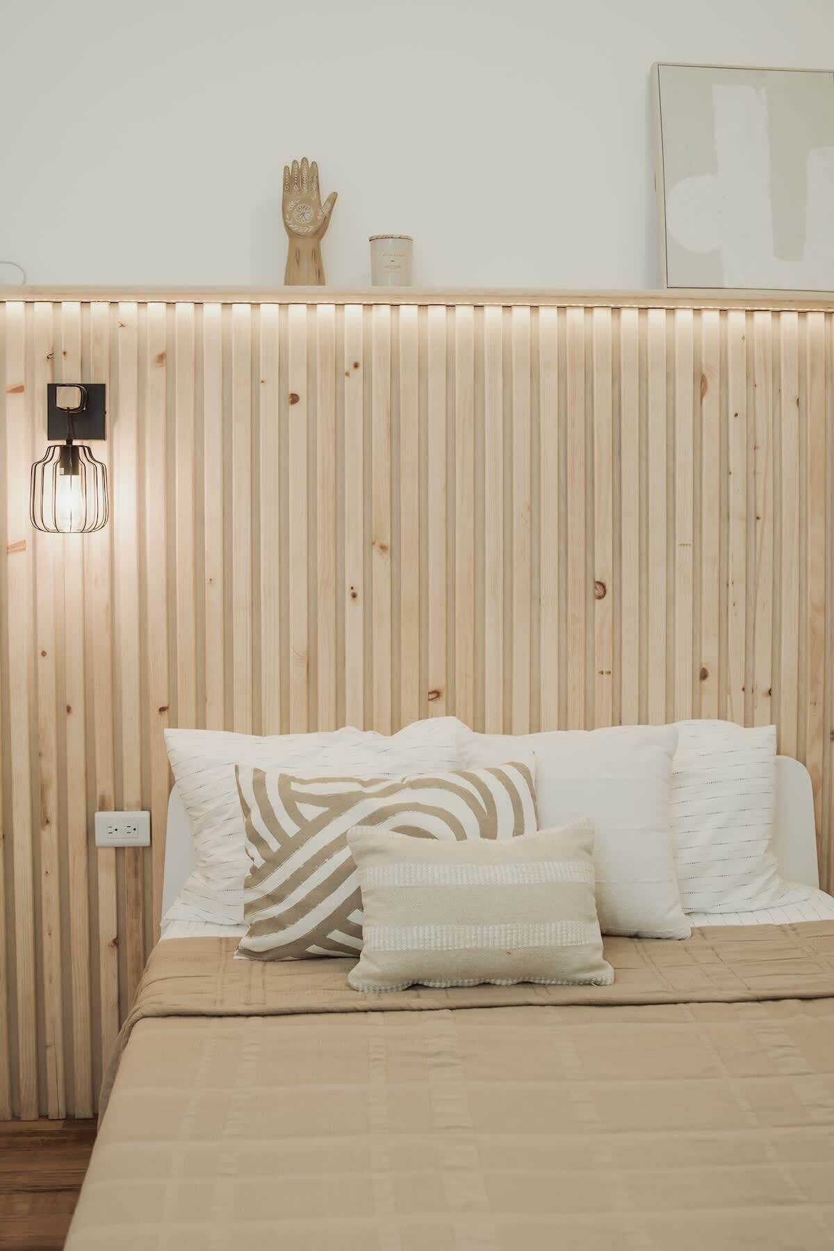 Ein Schlafzimmer mit einem Lattenrost, einer Nachttischlampe und einem Bett mit vielen Kissen.
