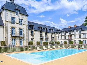 A hotel with a swimming pool, multiple balconies, and a traditional European architectural style.