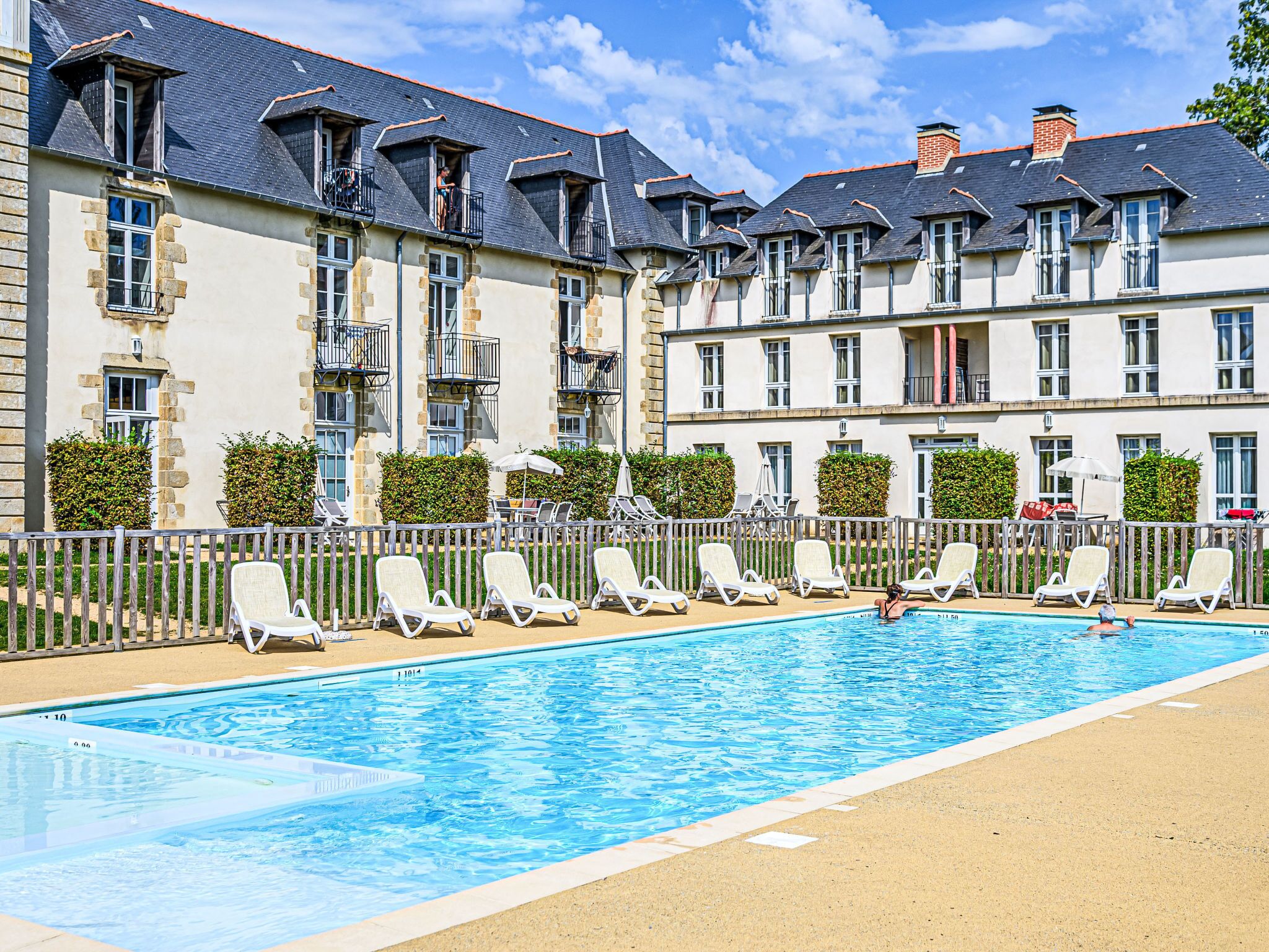 Um hotel com piscina, várias varandas e cadeiras de lounge.