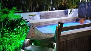 Una escalera de madera que lleva a una zona de piscina rodeada de abundante vegetación.
