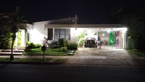 Una casa moderna con entrada de coches, un coche estacionado en el garaje y una entrada bien iluminada.