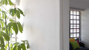 Una habitación con una cama, una planta en maceta y una ventana con barrotes.