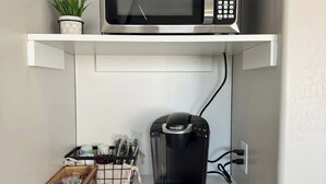 A compact kitchenette with a microwave, coffee maker, and a small refrigerator.