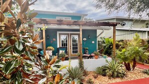 A house with a covered porch, potted plants, and a red pathway.