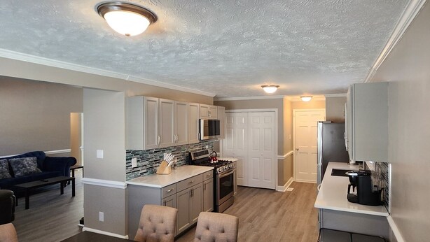 A compact kitchen with a microwave, stove, and a coffee maker on the counter.
