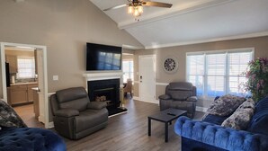 A living room with a fireplace, two sofas, a coffee table, and a TV mounted on the wall.